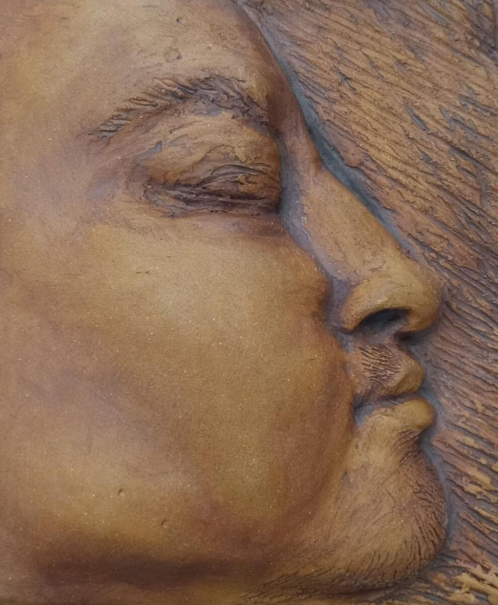 Nonbinary 1 Small bas relief (tile) of a nonbinary person's facial profile by Shane Brodie. Eyes are closed. Surface texture such a hair and wrinkles are emphasized by dark reddish brown iron oxide.