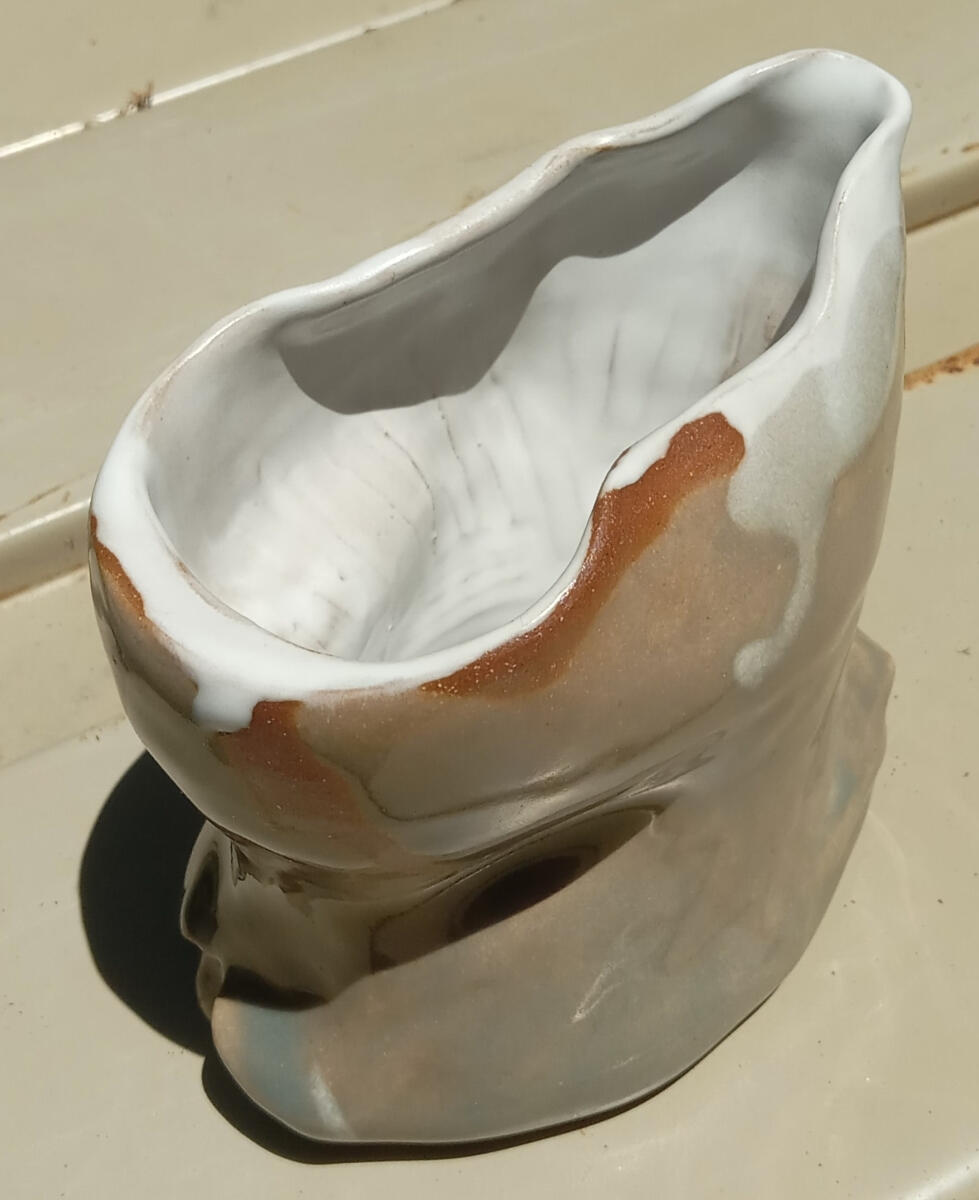 Organic creamer Handle-less, dimpled creamer by Shane Brodie. There is a depression running around the outside piece where you are meant to place your hand for holding and pouring. Glazed light green with a white liner.