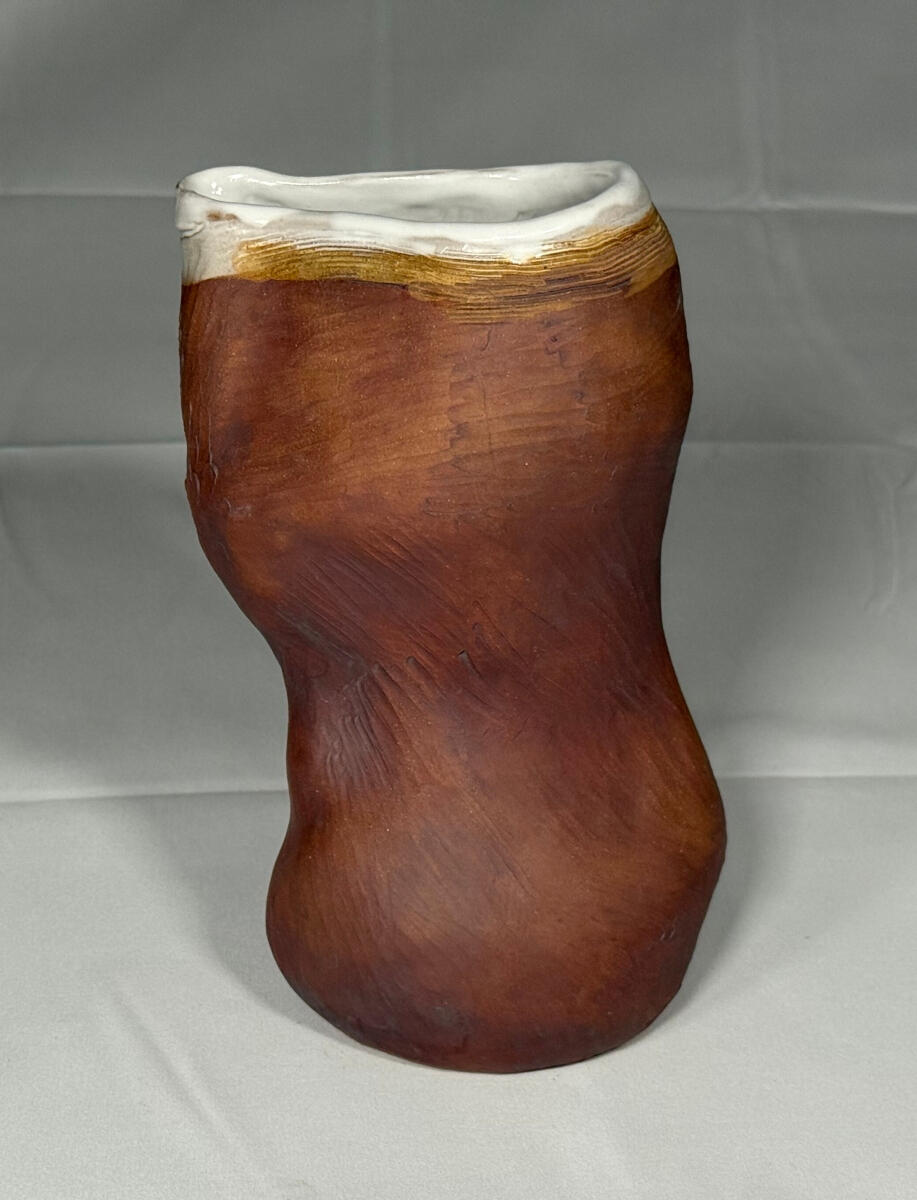 Throated pitcher 1 Tall handle-less pitcher with a defined spout throat by Shane Brodie. The heavily striated surface is unglazed, but is rusty red from iron oxide staining. The inside and rim are covered with a white glaze.