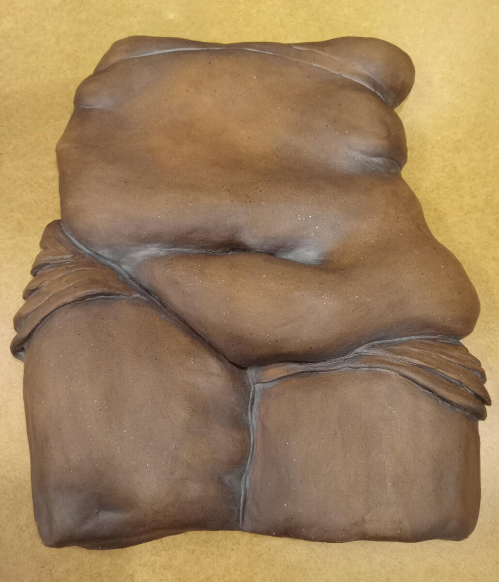 Nonbinary 2 Bas relief sculpture of a nonbinary person's torso and thighs by Shane Brodie. surface is very smooth and burnished. Wrinkles and folds in fabric or skin are emphasized by the application of iron oxide to the piece.